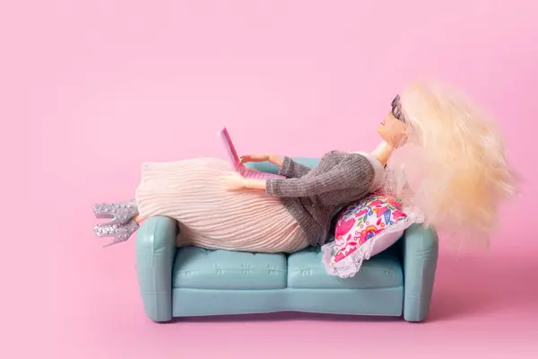 Doll with laptop on sofa. Working or relax at home, freelance creative concept