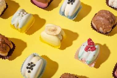 Sarı arka planda, düz bir zeminde farklı badem kurabiyeleri. Lüks tatlılar.