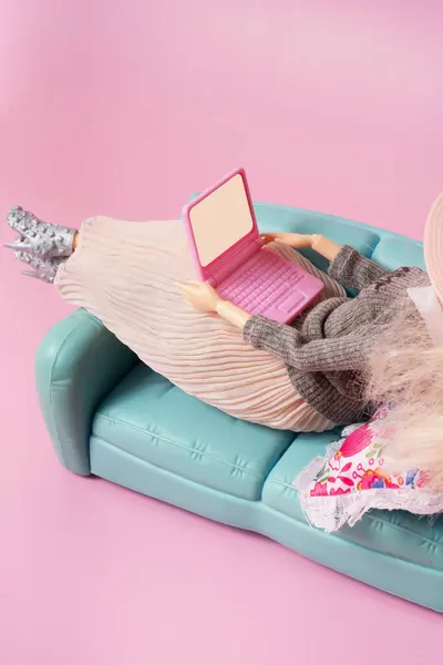 Doll with laptop on sofa. Working or relax at home, freelance creative concept