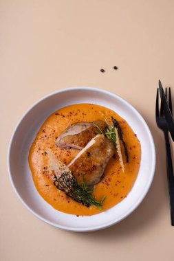 Kızarmış tavuk, havuç ve patates püresi ile bej arka plan manzaralı siyah çatal bıçak takımı..
