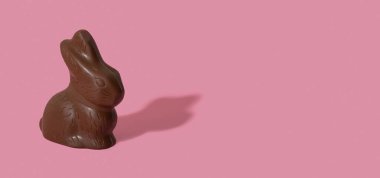 Chocolate rabbit symbol to Easter holidays isolated n a pink banner background with copy space