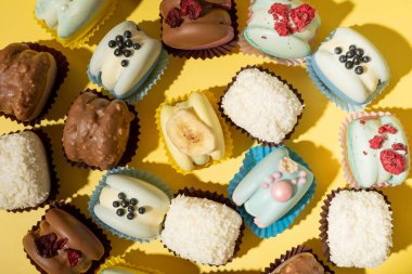 Sarı arka planda farklı badem kurabiyeleri, düz bir zemin.