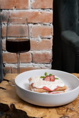 Kafedeki ahşap bir masada çilekli waffle ve krema sosu..