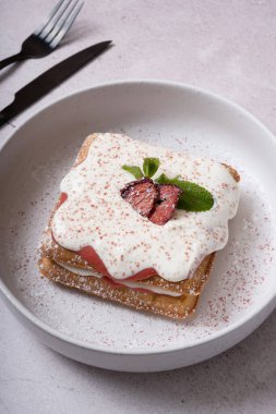 Gri arka planda çilekli waffle ve krema sosu.