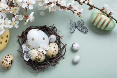 Yuvasında çiçeklerle Paskalya yumurtaları ve pastel yeşil arka planda kelebekler..