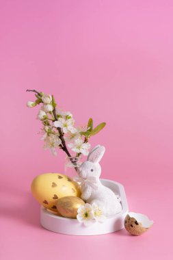 Beyaz tavşan, çiçek dalı ve pembe arka planda Paskalya yumurtası..