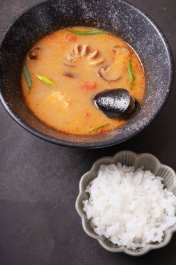 Tom deniz ürünleri ve pirinç karışımı koyu arkaplan manzaralı lezzetli çorba.