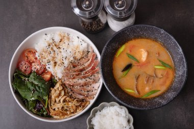 Tom yer elması çorbası deniz ürünleri ve kase pirinç, dana eti ve sebzeli koyu arkaplan manzaralı..