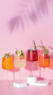 Renkli yaz alkollü kokteylleri ve pembe arka planda palmiye gölgesi.
