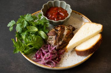 Bir tabak kızarmış domuz eti, ekmek, sos ve yeşillik..