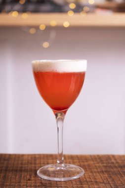 Ahşap bir masanın üzerinde çırpılmış kremalı kırmızı kokteyl..