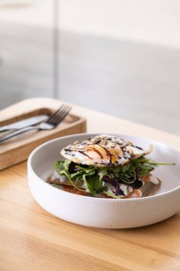 Somon, yumurta ve çekirdekli güzel bir tabakla ahşap kafe masası manzaralı beyaz tabak..