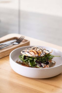 Somon, yumurta ve çekirdekli güzel bir tabakla ahşap kafe masası manzaralı beyaz tabak..