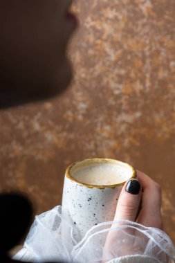 Kadın elinde balkabaklı latte. Bardağı sıcak içecekle tutan eller..