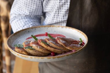 Garsonun elinde bir tabak balkabaklı pankek. Sonbahar menü kavramı.
