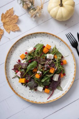 Salata, yeşillik, kabak ve ahşap arka planda yumuşak peynir tabağı. Sonbahar menü kavramı