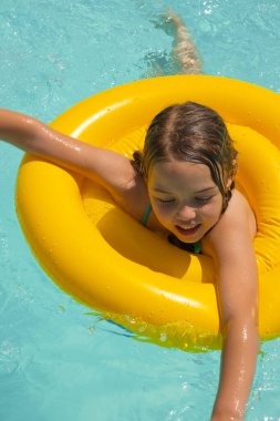 5 yaşında bir kız havuzda şişirilebilir bir çemberle yüzüyor..