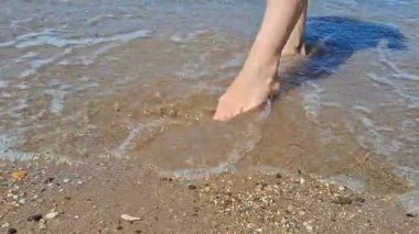 Huzurlu sahil boyunca berrak sularda yürürken dingin dalgaların tadını çıkarıyorum.