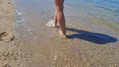 Çıplak ayakla kumlu bir sahilde, yumuşak deniz dalgalarının yanında yürüyorum.