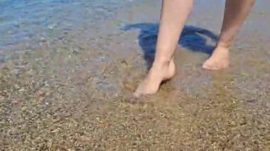 Huzurlu sahil boyunca berrak sularda yürürken dingin dalgaların tadını çıkarıyorum.