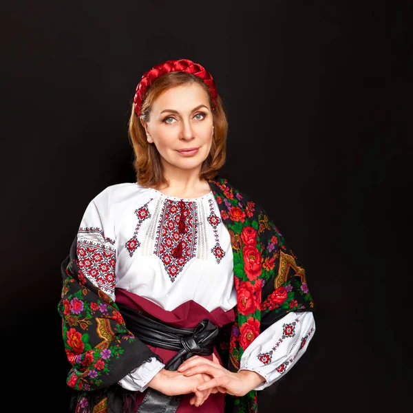 Beautiful Ukrainian woman in national costume. Attractive Ukrainian woman wearing in traditional Ukrainian embroidery, at black background.