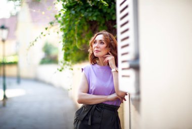 Güzel orta yaşlı kadın sokak fotoğraf çekiminde poz veriyor.