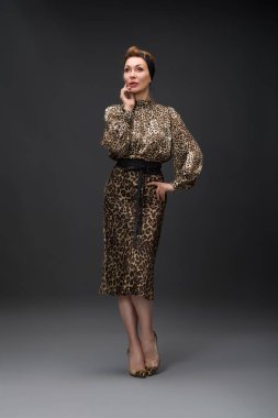 Leopar deseni ve nötr tonlar da dahil olmak üzere çeşitli şık giysiler içinde bir modelin yer aldığı bir moda fotoshoot. Görüntüler, modern ve klasik tarzları gösteren dinamik ve anlamlı pozları vurgular..