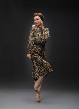 Leopar deseni ve nötr tonlar da dahil olmak üzere çeşitli şık giysiler içinde bir modelin yer aldığı bir moda fotoshoot. Görüntüler, modern ve klasik tarzları gösteren dinamik ve anlamlı pozları vurgular..