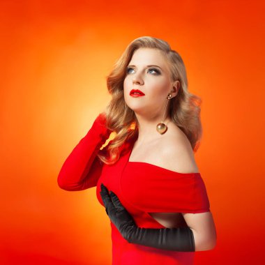 A glamorous young woman with styled blonde hair wearing a vibrant red dress and bold makeup. She poses elegantly against a vivid orange background, exuding sophistication and confidence. clipart