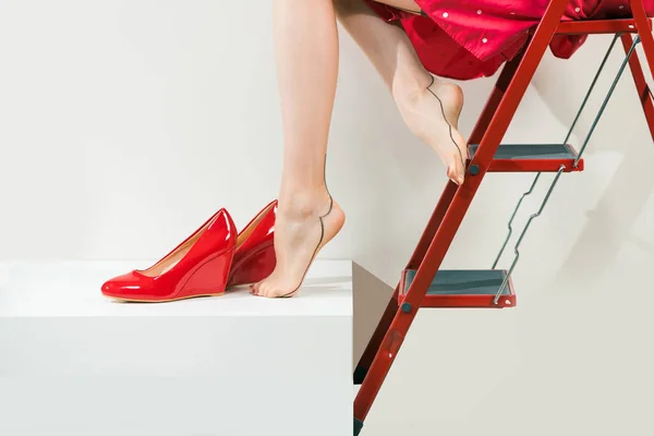 穿着红衣服 脚上穿着红鞋子 脚上穿着旧式茶色长袜的年轻女子 图库图片