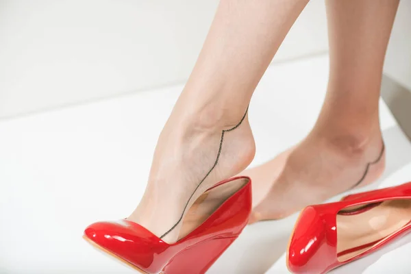 穿着红衣服 脚上穿着红鞋子 脚上穿着旧式茶色长袜的年轻女子 免版税图库照片