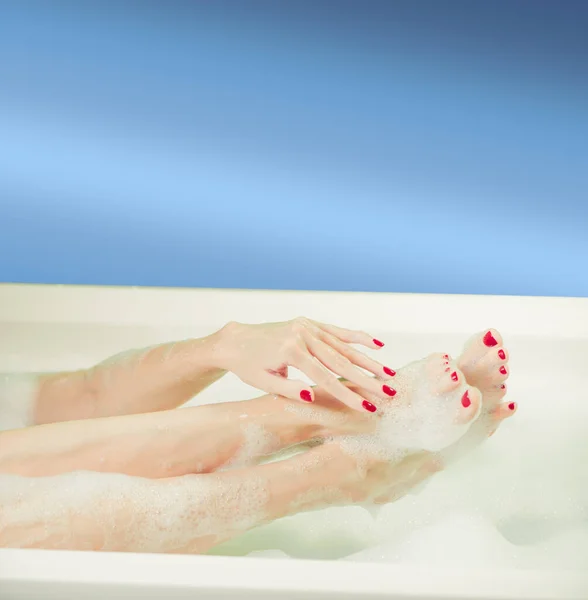 白い風呂の中に泡で覆われた若い女性の手と足 — ストック写真