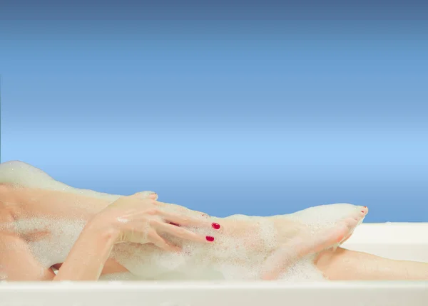年轻女子的手和脚被白浴中的泡沫覆盖着 免版税图库图片
