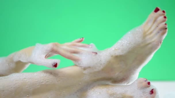 绿色背景的泡泡浴泡沫中年轻的高加索女性身体部位 — 图库视频影像
