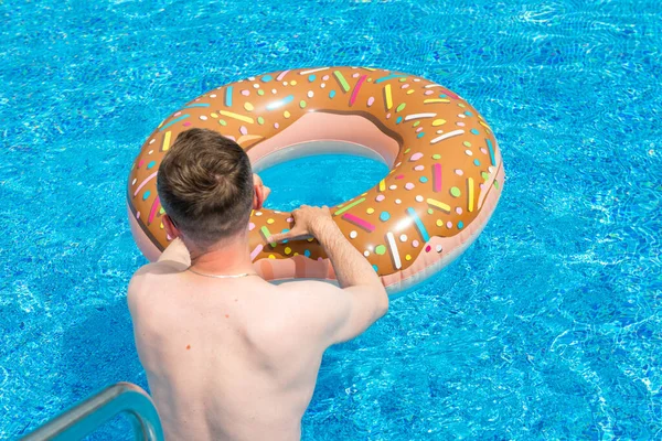 年轻人 带着橡皮圈在更舒适的游泳池里 图库照片