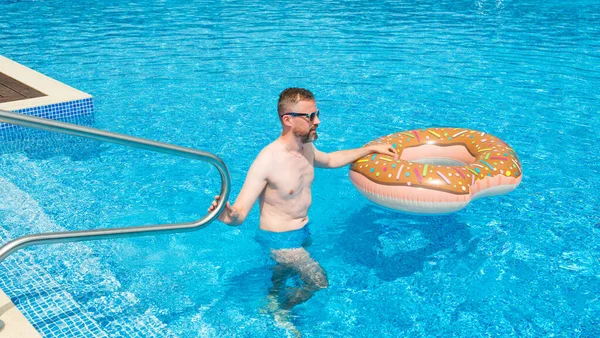 年轻人 带着橡皮圈在更舒适的游泳池里 免版税图库照片