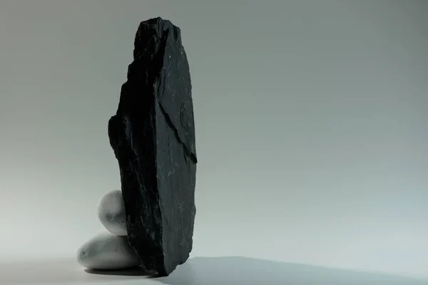 一块黑色大扁平石头后面的白色小光滑石头 免版税图库图片