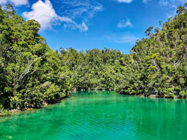 Huzurlu, gök mavisi bir gölün üzerinde yükselen tepelerin resimsel bir görüntüsü..