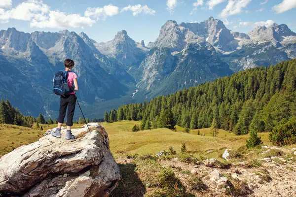 石の岩の上に立ってイタリアのドロマイト山脈の美しい風景を見る女性のハイカー ロイヤリティフリーのストック写真