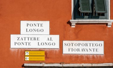 Venedik, İtalya 'da bir ev duvarında sokak isminin yazılı olduğu tabelalar, Venedik istikametine yakın plaketler ve tabelalar.