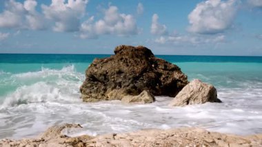 Okyanus dalgaları yazın tropikal arı üzerinde kayalara çarpıyor.