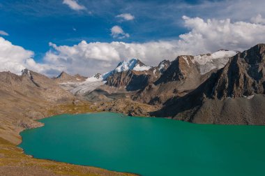 Alakel, dingin bir turkuaz göl, yüksek, engebeli dağlarla, engin ve açık mavi gökyüzünün altında, dağlık bölgelerde dokunulmamış doğayı yansıtan karla kaplı tepelerle kucaklanıyor.
