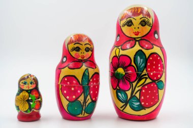 Rus matryoshka yuva yapma bebekleri, halk motifleriyle elle boyanmış, kırmızı çiçek süsü, kültürel el işi, süs eşyaları, Rus mirasının sembolü, ahşap oyuncaklar. Beyaz arkaplan