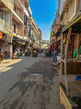 25 Nisan 2024, Yeni Delhi, Hindistan. Kirli cadde. Karşıdan karşıya geçen yayalar, yük ve yolcu taşıyan çekçekçekler. Şehirde bir ara sokak, insanlarla ve dükkanlarla dolu renkli cephelerle dolu.