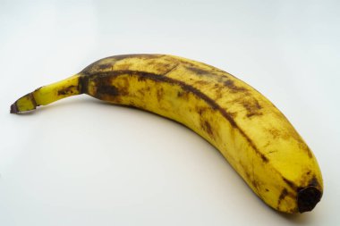 Beyaz arka planda kahverengi benekli olgun bir muz gösterilir. Olgun meyve ve yiyecek atıkları kavramı