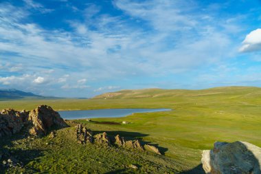 Alp çayırları ve dağ gölü, karlı tepeler, yemyeşil, bulutlu gökyüzü. Doğa aşıkları için ideal huzur, manzara güzelliği ve doğa maceraları için yürüyüş ve keşif gibi..