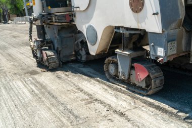 Eski asfalt katmanını öğütüp kaldıran sürüngen raylarıyla donatılmış büyük asfalt değirmen makinesi, şehir altyapı iyileştirme projesinde yeni asfalt uygulamasına hazırlanıyor.