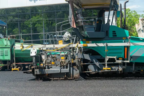 Asfalt hammer makinesi hazır yol yatağı üzerine sıcak bitumen karışımı yayar, ardından pürüzsüz yüzey bitimi için sıkıştırıcı, kentsel altyapı gelişimi ve otoyol geliştirme sürecini gösteren.