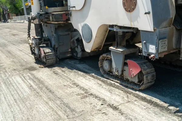 Eski asfalt katmanını öğütüp kaldıran sürüngen raylarıyla donatılmış büyük asfalt değirmen makinesi, şehir altyapı iyileştirme projesinde yeni asfalt uygulamasına hazırlanıyor.