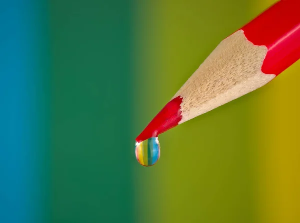 赤い鉛筆の水滴に反射する虹色 ロイヤリティフリーのストック写真